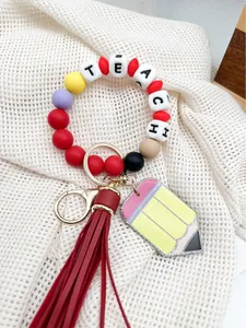 Detalle del llavero de cuentas de silicona para maestros con lápiz y borla roja vibrante.