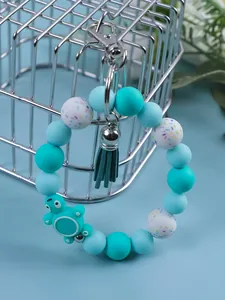 Close-up detail of a cute silicone beaded keychain featuring a turtle charm and green tassel
