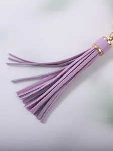 Macro-detail van een paarse lederen kwastjes-sleutelhanger met een gouden metalen kap.