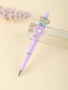 Detailed view of purple beaded ballpoint pen with butterfly and flower acrylic charms