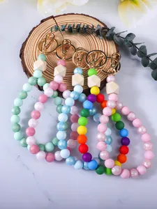 Set di portachiavi in perline di silicone colorate su un supporto in legno rustico.