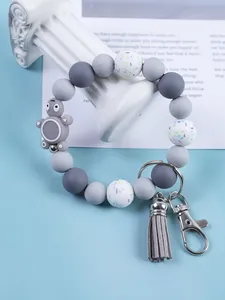 Detail showing a cute silicone turtle charm and grey tassel on a stylish beaded keyring