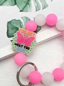 Detalle de llavero de cuentas de silicona rosa y blanco con dije de mariposa inspirador