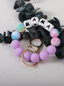 Gros plan d'un porte-clés en perles de silicone avec lettres MAMA et motifs galaxie.