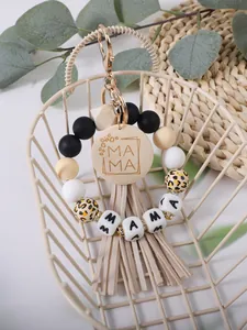 Close-up van een MAMA siliconen kralen sleutelhanger met beige kwastjes en luipaard kralen.