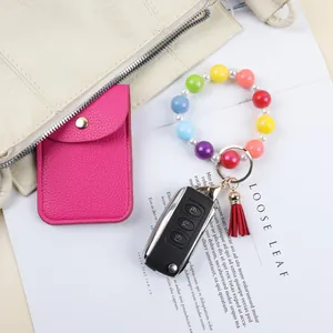 Macaron colored silicone bead bracelet keychain with small red tassel and gold ring.