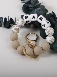 Gros plan du porte-clés en silicone MAMA avec fermoir doré et perles à motifs floraux