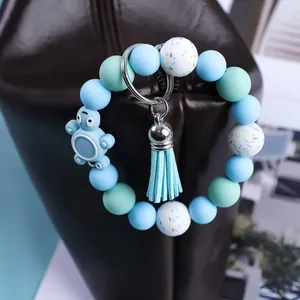 Cute silicone bead keychain with turtle charm and tassel shown on a leather bag