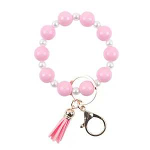 Pink and white silicone bead bracelet keychain with matching tassel on white background