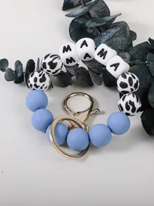 Détail macro de perles MAMA et perles en silicone imprimé vache sur un porte-clés bleu
