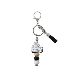 Handmade silicone keychain featuring coffee cup book stack design and black tassel