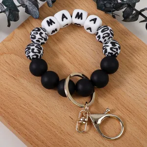 Porte-clés bracelet en silicone imprimé léopard Mama avec anneau doré sur fond bois