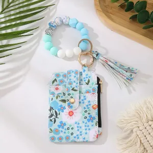 Blaue Leder-Kartentasche mit Gänseblümchen-Print, Perlenarmband und Quasten-Anhänger