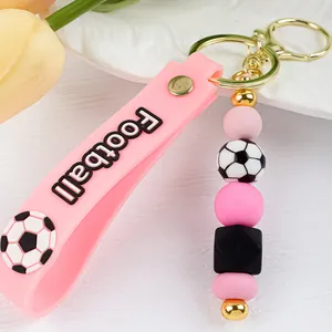 Detalle de llavero de fútbol de silicona rosa con correa de cuentas y dije de balón