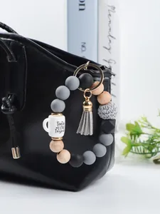 Close-up detail of silicone bead keychain bracelet with cup charm on a black bag