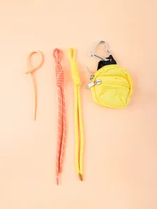 Gros plan sur une mini pochette jaune avec mousqueton coeur et lanières tressées.
