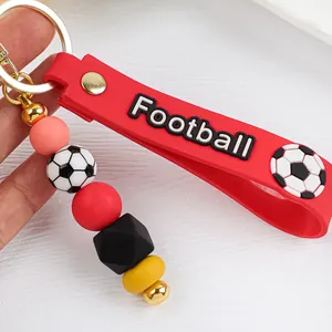 Detalle de llavero de fútbol de silicona roja con cuentas y cierre dorado.