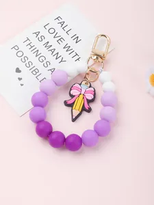 Detailed view of purple silicone beaded keychain featuring a cute pencil and bow charm.