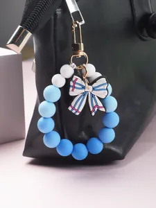 Detail view of a blue and white silicone beaded keychain with a bow charm on a black bag