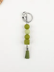 Detail view of various green silicone beads and a matching tassel on a silver keychain loop.