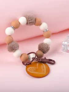 Detailaufnahme von Silikonperlen-Schlüsselanhänger mit Kunstfell-Pompons und Holzanhänger