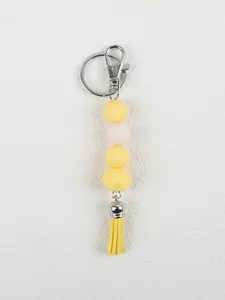 Detailed view of the yellow silicone beads and leather tassel on this creative keychain.