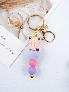 Detailed view of a cartoon highland cow keychain with silicone beads and pompom.