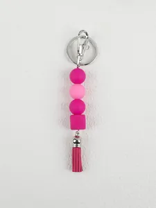 Close-up detail of a pink silicone bead keychain featuring a leather tassel and silver clasp