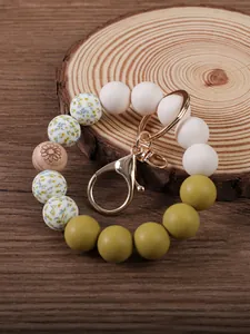 Close-up detail of silicone beaded wristlet keychain with floral print and wood bead.