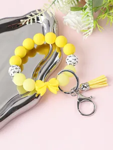 Gedetailleerde weergave van gele siliconen kralen armband sleutelhanger met strik en kwastje