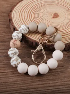 Close-up of silicone beaded keychain with leaf patterns on a rustic wood surface