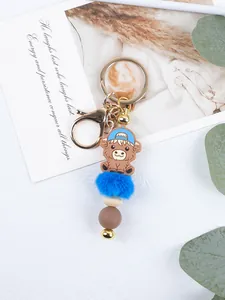 Close-up detail of a cute cartoon cow keychain with blue pom pom and silicone beads