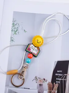Close-up detail of cartoon sun and book charm keychain with vibrant silicone beads