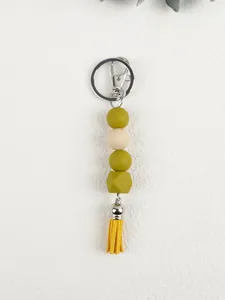 Detail of silicone bead keychain featuring olive beads and a bright yellow tassel
