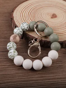 Detail of silicone beaded keychain with leaf print and natural wood bead on wood base