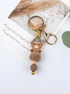 Detailed view of a cute cartoon highland cow keychain with brown pompom and beads