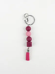 Detailed macro view of a silicone bead keychain featuring a pink tassel and silver metal clasp