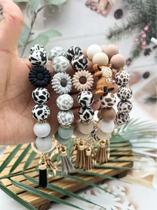 Detailed view of silicone bead wristlet keychains with daisy and highland cow charms