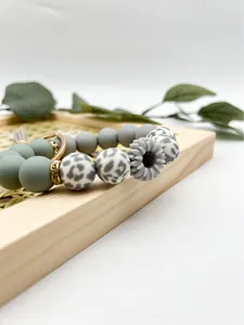 Detailed macro view of a silicone bead keychain featuring a grey daisy and leopard pattern
