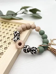 Detail of daisy silicone bead wristlet keychain with leopard print and leather tassel