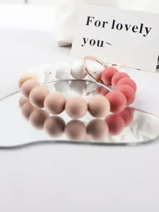 Close-up view of candy-colored silicone bead keychain with rose gold ring on mirror