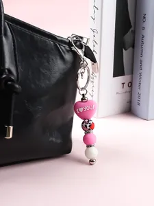 Gros plan d'un porte-clés en perles de silicone coeur rose sur un sac noir.