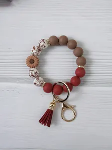 Detailed view of daisy silicone bead wristlet keychain with red tassel and gold clasp.