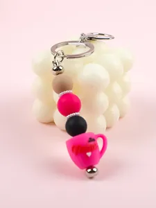 Gros plan du charm tasse rose vif et des perles en silicone sur un porte-clés en métal élégant