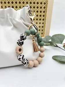 Close-up detail of a daisy silicone bead wristlet keychain with tassel on a white bag