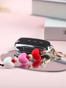 Gros plan d'un porte-clés en perles de silicone en forme de cœur sur un miroir rose.