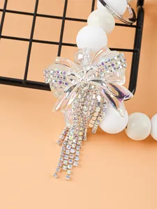 Nahaufnahme eines weißen Silikon-Schlüsselanhängers mit einer glitzernden Strass-Schleife