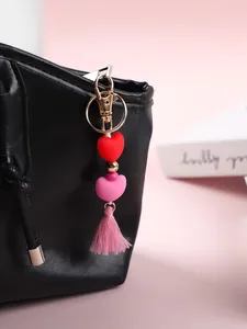 Détail d'un bijou de sac en silicone avec cœurs, pompon rose et clip