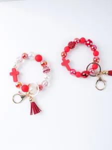 Detailed view of silicone beaded bracelet keychain with cross and red tassel
