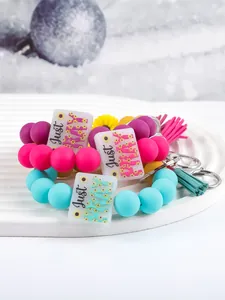 Detailed view of silicone bead wristlet keychains with Just PRAY plaque and tassels.